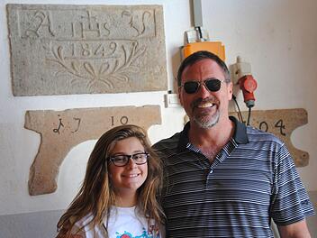 Greg Fondran mit Tochter Jadyn vor dem Sandstein, den ihr UrUrUrGroßvater Adam Vorndran einst angefertigt hat.  Foto: Anton Enders