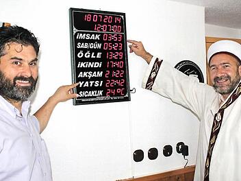 Der Vorsitzende der muslimischen Gemeinde Lichtenfels, Ali Cakir (links), und der Hodscha Ramazan Ölmez erklären, was die Wörter und Uhrzeiten auf der Digitaluhr für die Muslime zu bedeuten haben. Foto: Markus Häggberg
