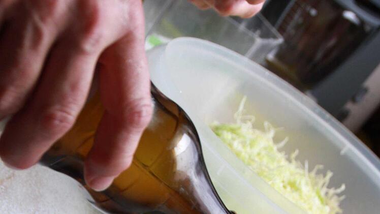 Essig, Öl, Zucker und Salz zusammen aufkochen lassen und unter die Kohl-Streifen mengen.