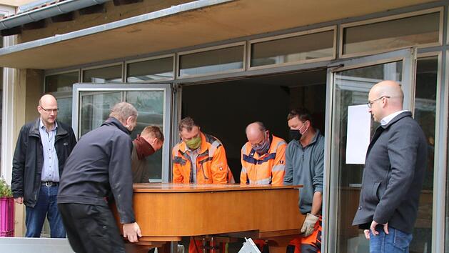 Die Mitarbeiter des Bauhof tragen den schweren Flügel in die neue Musikschule. Viel schwieriger war es, ihn aus der Zehntscheune zu holen. Schulleiter Thomas Reuß (links) und Bürgermeister Michael Kastl (rechts) haben den Umzug seit Wochen vorbereitet. Foto: Thomas Malz