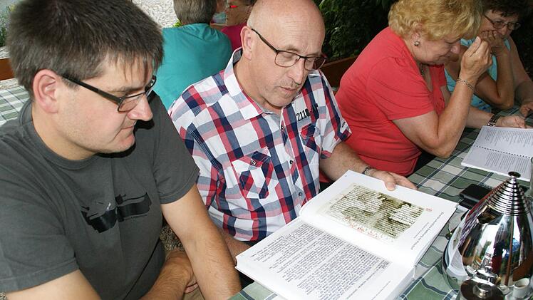Einen ersten Blick in das Prölsdorfer Ortsbuch gewährten beim Wirtshaussingen der Senioren der Gemeinderat Frank Schilling und der Vorsitzende des Festkomitees, Berthold Moser (von links).