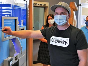 Ein junger Mann zahlt seine KFZ-Geb&uuml;hr am Automaten neben der Kreiskasse. Wenn notwendig, helfen die Mitarbeiter weiter.