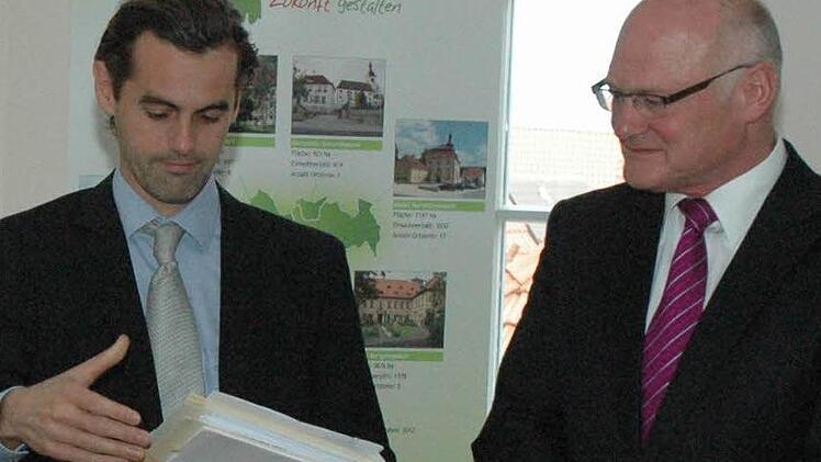 Christian Heck (links) überreichten an Wolfgang Borst (rechts) den Bewilligungsbescheid zum Umbau der alten Schule Rügheim.
