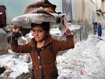 Winter in Afghanistan: Ein Mädchen trägt Brote auf dem Kopf, während es durch den Schnee geht. Das Bild entstand am 8. Februar dieses Jahres in Kabul, der Hauptstadt Afghanistans. Foto: Hussein Malla/AP/dpa