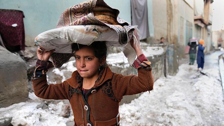 Winter in Afghanistan: Ein Mädchen trägt Brote auf dem Kopf, während es durch den Schnee geht. Das Bild entstand am 8. Februar dieses Jahres in Kabul, der Hauptstadt Afghanistans. Foto: Hussein Malla/AP/dpa