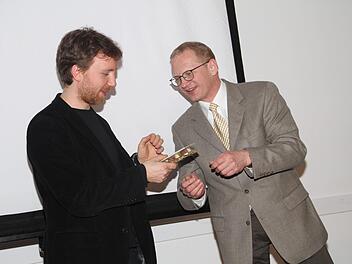 Otmar Fugmann, Geschäftsführer der Friedrich-Baur-Stiftung (rechts)  überreicht Richard Siedhoff ein Gastgeschenk.