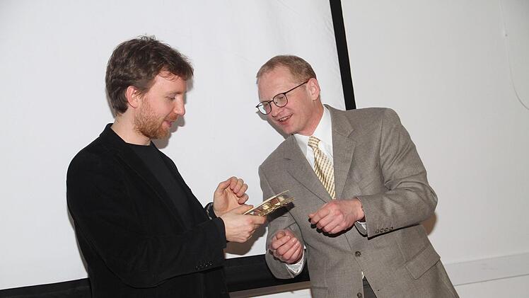 Otmar Fugmann, Geschäftsführer der Friedrich-Baur-Stiftung (rechts)  überreicht Richard Siedhoff ein Gastgeschenk.