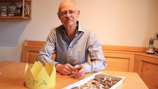Bernhard Christoph wird dem nächsten Lichtenfelser Stadtrat und dem  Kreistag nicht mehr angehören. Vor ihm liegen symbolisch eine "Opa"-Krone, denn er möchte sich künftig mehr seiner Familie widmen, und die Fundstücke eines Feldes bei Lahm, wo ein steinzeitliches Dorf stand und seine Frau Rosi  am Dreikönigstag   den Bronze-Armreif fand, den er in Händen hält. Foto: Matthias Einwag
