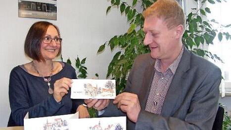 Die von ihr gestalteten Karten zeigt Künstlerin Silvia Huber im Sonnefelder Rathaus Bürgermeister Michael Keilich. Sie hat für Sonnefeld, Hassenberg und Gestungshausen Motivvariationen angefertigt.  Foto: K. Oelzner