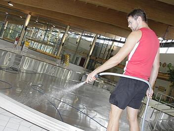 Oliver Dietl reinigt den Fliesenboden. Das Wasser im Becken ist abgelassen.  Foto: Andreas Oswald