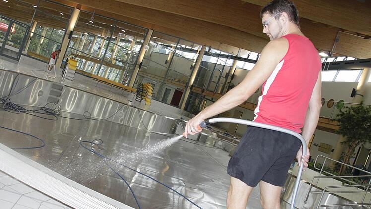 Oliver Dietl reinigt den Fliesenboden. Das Wasser im Becken ist abgelassen.  Foto: Andreas Oswald