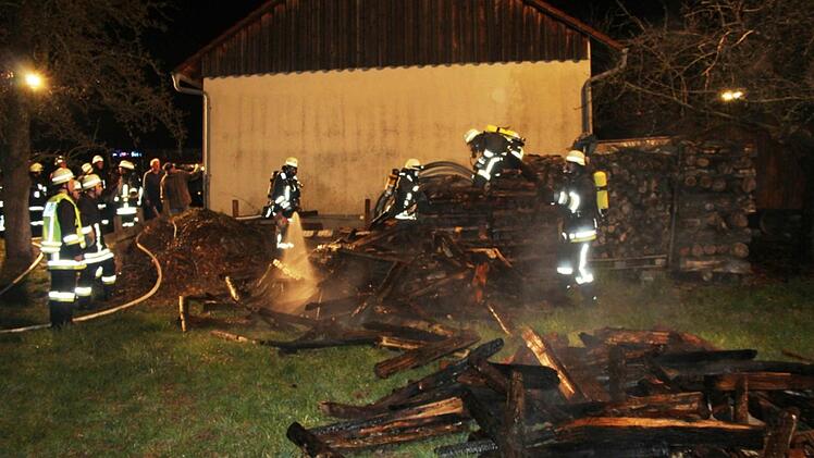 Die Feuerwehrleute l&ouml;schen die Glutnester im Holzsto&szlig;. Foto: Stefan Brunner