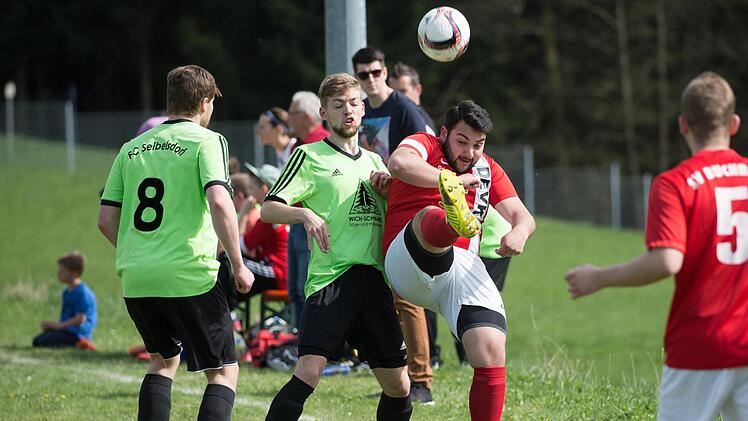 Der Buchbacher Ali Demir (rotes Trikot) spielt den Ball &uuml;ber Torsch&uuml;tze Niklas Klatt.  Foto: Heinrich Wei&szlig;