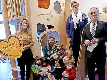 Elke Wuthe (oben rechts) und Erzieherin Johanna Seuß (auf der Treppe sitzend) freuten sich mit den Kindern über eine großzügige Spende für „Die Kita“, die Gerhard Zettel (rechts) und Nicole Neuber (links) von der VR Bank Oberfranken Mitte im Kinde...