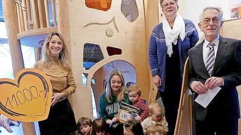 Elke Wuthe (oben rechts) und Erzieherin Johanna Seuß (auf der Treppe sitzend) freuten sich mit den Kindern über eine großzügige Spende für „Die Kita“, die Gerhard Zettel (rechts) und Nicole Neuber (links) von der VR Bank Oberfranken Mitte im Kinde...