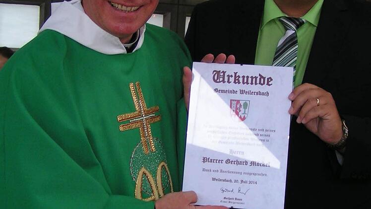 Bürgemeister Gerhard Amon überreicht an Pfarrer Gerhard Möckel eine Dankes- und Ehrenurkunde der Gemeinde Weilersbach. Foto: Heidi Amon