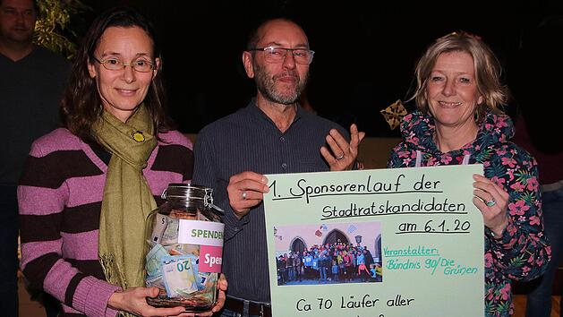 6148,50 Euro, den Erlös aus dem Spendenlauf der Stadtratskandidaten,  überreichten die Grünen-Kandidatinnen Petra Mesarosch (links) und  Christine Martin (rechts) in einem Glas an Charly Friedel (Mitte) vom  Mürschter Kinderhaus.  Foto: Dieter Britz
