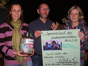 6148,50 Euro, den Erlös aus dem Spendenlauf der Stadtratskandidaten,  überreichten die Grünen-Kandidatinnen Petra Mesarosch (links) und  Christine Martin (rechts) in einem Glas an Charly Friedel (Mitte) vom  Mürschter Kinderhaus.  Foto: Dieter Britz