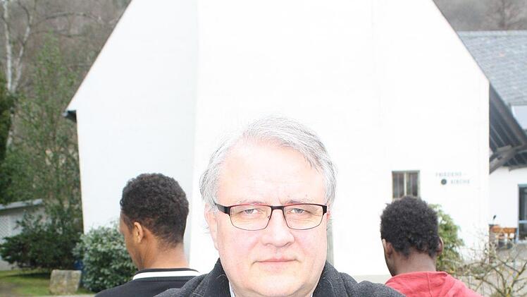 Pfarrer Gerd Kirchner vor seiner Kirche. Im Hintergrund stehen zwei Flüchtlinge, die hier Asyl gefunden haben. Foto: S. Will