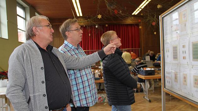Werner Jung (links)  im Gespr&auml;ch mit Vorsitzenden Matthias M&uuml;ller vor einer Stellwand, die Marken aus dem Lager Dachau zeigt. Geda V&ouml;lk