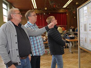 Werner Jung (links)  im Gespräch mit Vorsitzenden Matthias Müller vor einer Stellwand, die Marken aus dem Lager Dachau zeigt. Geda Völk