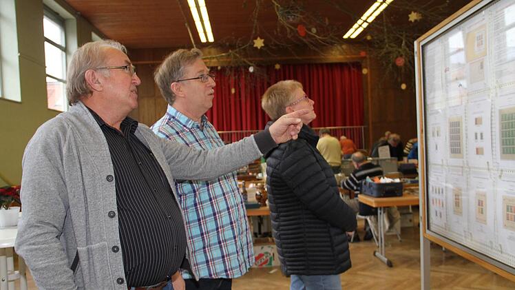 Werner Jung (links)  im Gespräch mit Vorsitzenden Matthias Müller vor einer Stellwand, die Marken aus dem Lager Dachau zeigt. Geda Völk