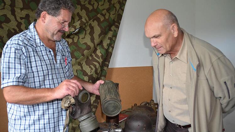 Sammler Harald Schneider (links) zeigte im Alten Forsthaus alte Ausrüstungsgegenstände deutscher Soldaten. Hier zeigt er Manfred Albert aus Steinach eine alte Gasmaske. Foto: Kathrin Kupka-Hahn