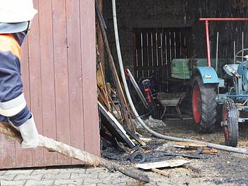 Ein Feuerwehrmann schiebt angekokelte Bretter beiseite. Foto: Arkadius Guzy
