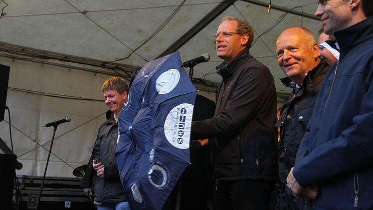 Bei der Eröffnung selber regnete es noch nicht. Aber dunkle Wolken hingen bereits bedrohlich über der Stadt. Bürgermeister German Hacker war aber für alle Fälle gut gerüstet. Fotos: Michael Busch