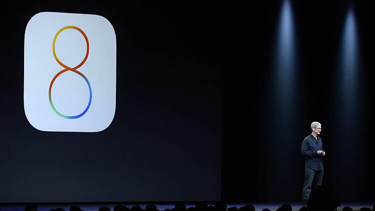 Tim Cook vor dem IOS 8-Logo Foto: John G. Mabanglo/dpa