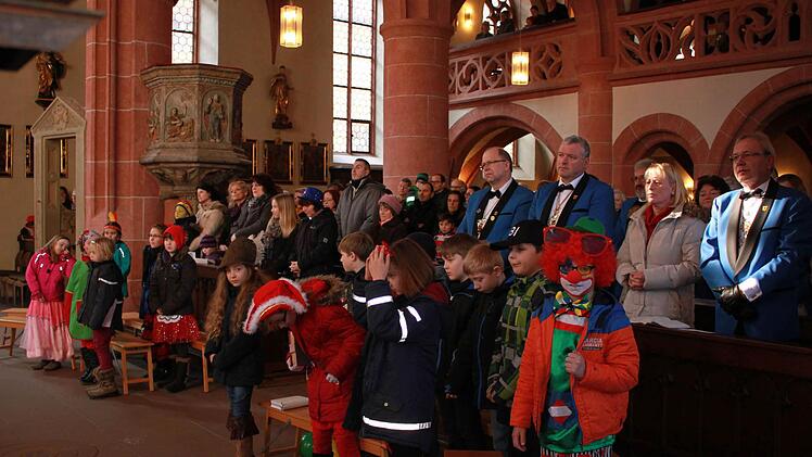 Der Elferrat hinter den maskierten Kommunionkindern.