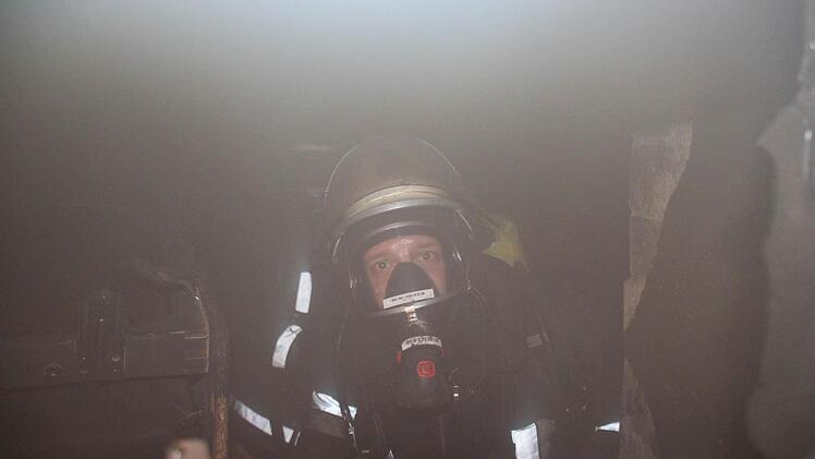 Ein Feuerwehrmann mit Schwerem Atemschutz am Brandherd hinter einem Kellerfenster  Foto: Friedwald Schedel