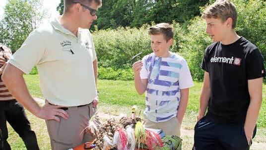 Moritz und Jonas Mertinke lassen sich von Holger Herold, dem Deutschen Meister im Fliegenbinden (von rechts), die Besonderheit des Fliegenfischens erklären.