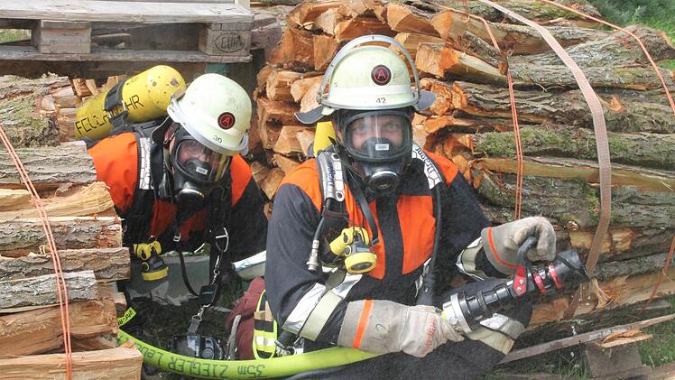 Zwei Atemschutzgeräteträger bei einer Übung. Das Wasser ihres Strahlrohrs soll die Feuerwehrleute im Ernstfall beim Vorgehen und während des Rettens in einem brennenden Gebäude sichern. Foto: Stephan Stöckel.