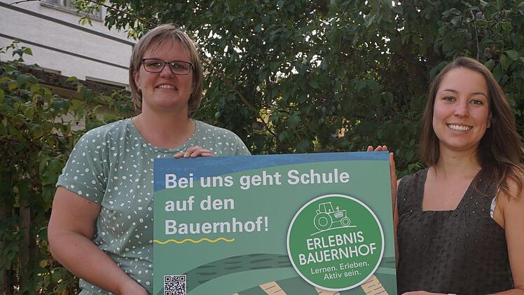 Anja Girz (links) ist zertifizierte Erlebnisbäuerin.  Jana Wagenländer (Ansprechpartnerin für Erlebnis-Bauernhöfe, Direktvermarktung und Bio-Regio am Amt für Ernährung, Landwirtschaft und Forsten) überreicht ihr eines der verlosten Schilder für ih...