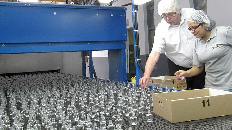 Zu den Aufgagen von Michael Neubauer (links) zählt unter anderem auch die Qualitätskontrolle der produzierten Glasflakons. Mit im Bild ist eine Mitarbeiterin.