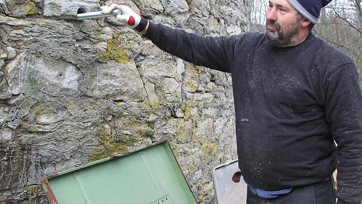 Zimmermann Harald Gräf steckt die Metallgewinde durch das Mauerwerk.
