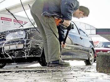 Ein Mann befreit sein Auto vom Winterschmutz. Foto: dpa