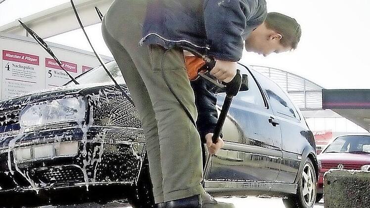 Ein Mann befreit sein Auto vom Winterschmutz. Foto: dpa