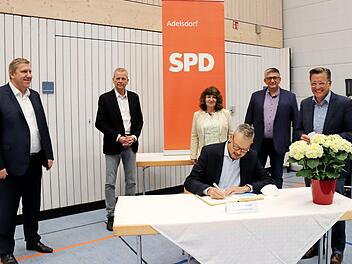 Peter Bofinger trägt sich als Erster ins Goldene Buch ein (stehend v. l.): Andreas Schwarz, Ulrich Maly, Martina Stamm-Fibich, Norbert Lamm und Karsten Fischkal.
