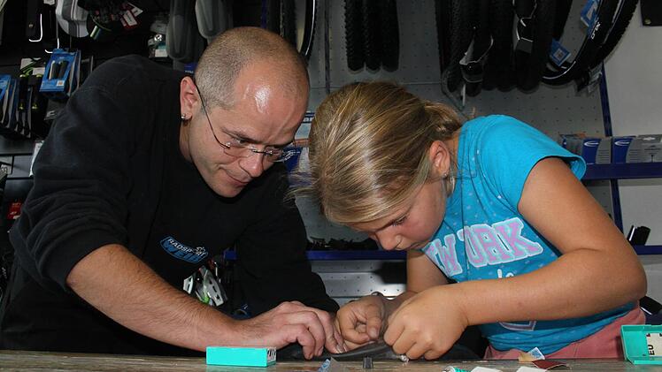 Christian Weiß zeigt der neunjährigen Amelie, wie man das Reparaturpflaster aufklebt. Fotos: Max Kaltenhäuser