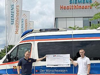 Der ehemalige Azubi bei Siemens Healthineers, Lucas Spörl (rechts), übergibt Lukas Hänsch vom ASB-Wünschewagen einen Scheck über 1600 Euro.