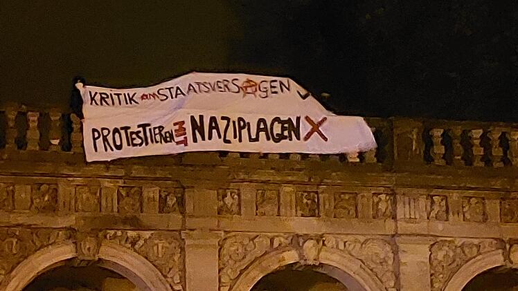 Vertreter den Antifa hissen auf den Arkaden ein Plakat gegen die Demonstranten.