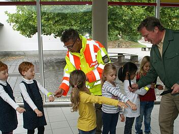 Die Haßfurter Erstklässler waren mit die ersten, die von der Kreisverkehrswacht mit reflektierenden Klickbändern ausgestattet wurden. Da traten die Buben und Mädchen gerne an, um sich von Stefan Scherrer (links) und Dominique Heim die Geschenke direkt an die Handgelenke legen zu lassen. Foto: Sabine Weinbeer