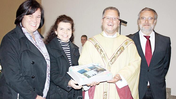 Pfarrgemeinderätin Sandra Ultsch, Pfarrgemeinderatsvorsitzende Katja Quidenus, Pfarrer Lars Rebhan und als Vertreter der Kirchenverwaltung Franz Wachter (von links) bei der Übergabe des Kuchens als Willkommensgeschenk Foto: Thomas Micheel