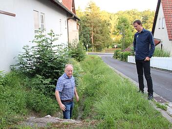 Bürgermeister Helmut Blank (links) und Planer Frank Braun stehen im bzw. am offenen Wassergraben im Kleinwenkheimer Sonnenweg. Hier sollen 2020 Verbesserungen kommen.Heike Beudert