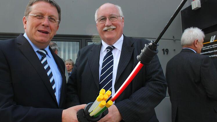 Oberbürgermeister Henry Schramm (CSU, links) und Regierungspräsident Wilhelm Wenning zeigen ein Glasfaserkabel, wie es im Industriegebiet verlegt wird. Fotos: Jürgen Gärtner