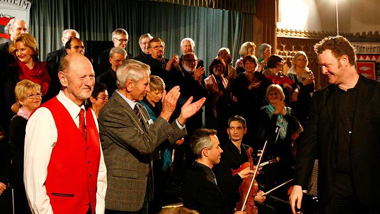 Die Helden des Abends: Der Komponist der "Fränkischen Weihnacht, Karl Haus, applaudiert dem Dirigenten des Forchheimer Liedervereins Jens Birnbach; Autor Reinhold Schmitt (rote Weste). Fotos: Neubauer