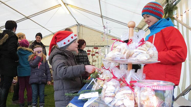 Früh übt sich: Die junge Plätzchenverkäuferin beim Euerdorfer Weihnachtsmarkt mit den selbst gebackenen Köstlichkeiten. Die Kundschaft scheint auf jeden Fall angetan von dem Angebot. Foto: Doris Bauer
