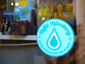Der "Refill"-Aufkleber an der Eingangstüre verheißt kostenloses Trinkwasser für Nachfüller. Foto: Nikolas Pelke